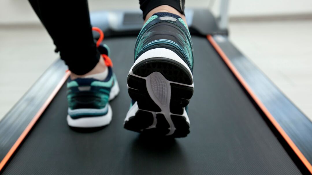 Ein Laufband - darauf sind die Füße einer trainierenden Person zu sehen - als Symbol für unsere Schreibtrainings
